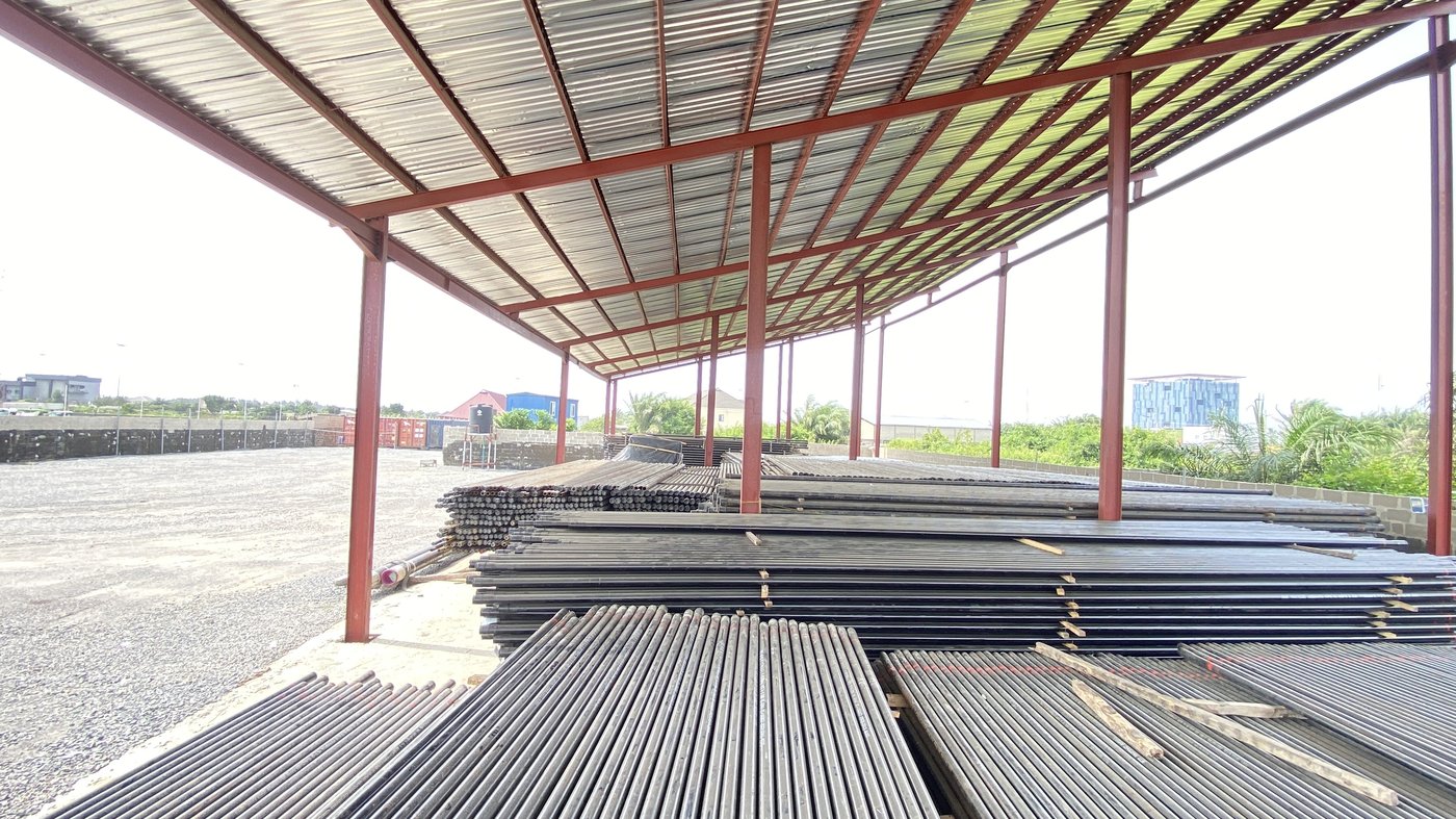 Rows of OCTG steel casing pipes stacked at a Nigerian storage yard under a covered shelter
